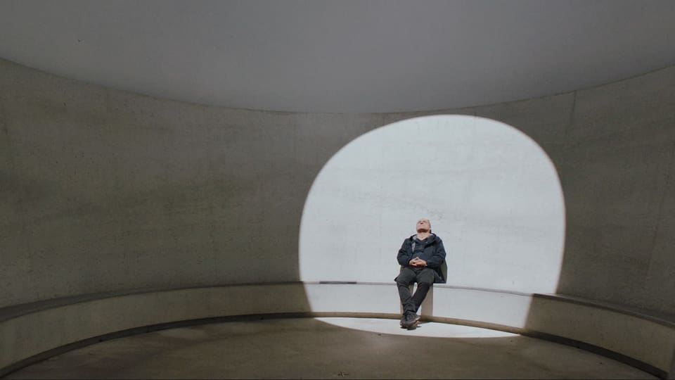 Ein Mann sitzt in einem Gebäude und wird beleuchtet