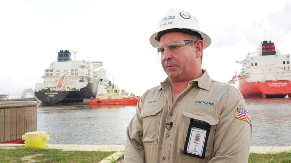 Mann mit Helm vor zwei Tankschiffen.