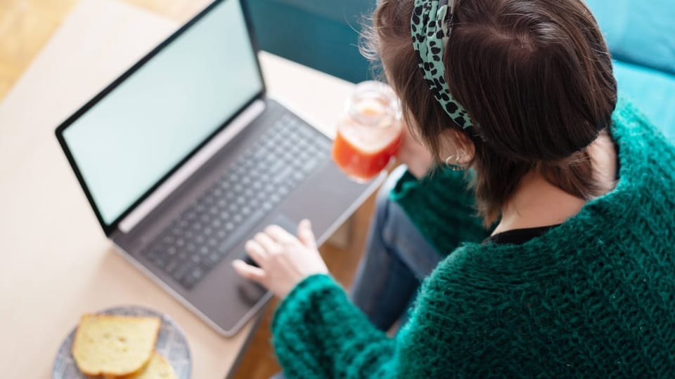 eine junge Frau sitzt zu Hause an ihrem Laptop