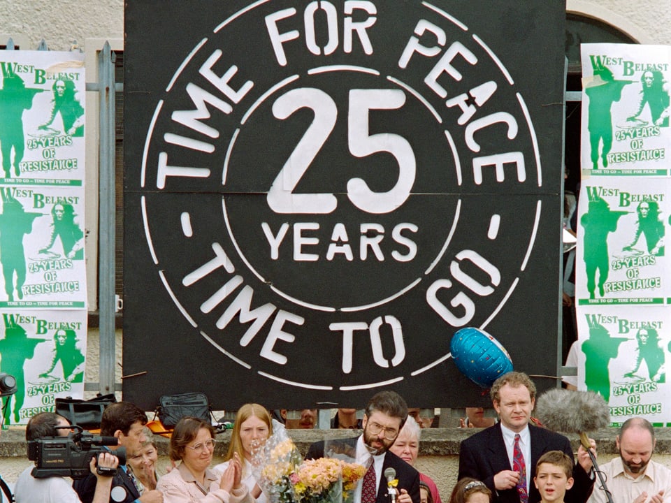 Plakat mit «Time for Peace»-Aufdruck, Menschenmenge davor.