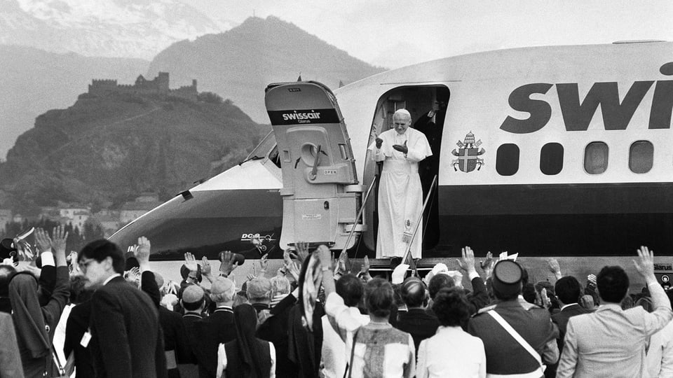 Papst Johannes Paul II winkt von der Tür einer Swissair-Maschine.
