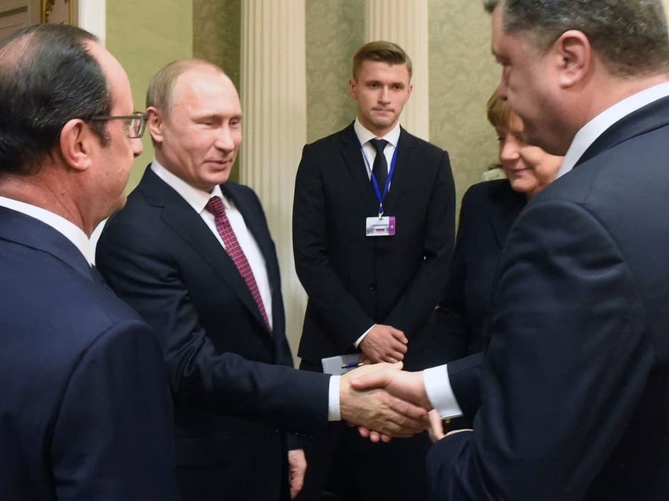 In Anwesenheit von François Hollande und Angela Merkel geben sich Russlands Präsident Putin und der ukranische Präsident Poroschenko im Februar 2015 die Hand.