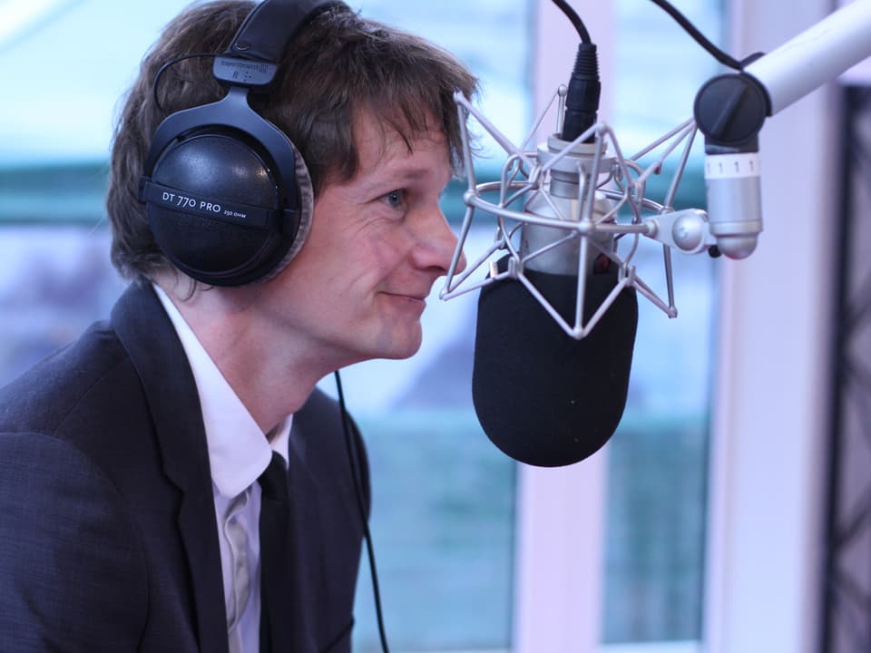 Der Slam Poet Christoph Simon sitzt in der Glasbox vor dem Mikrofon