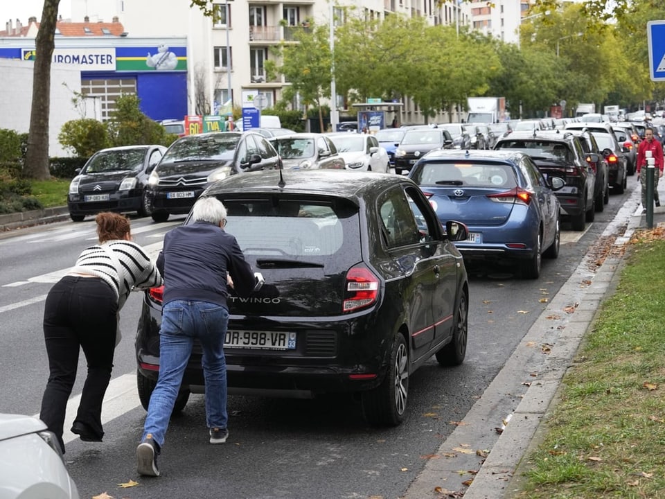 Menschen schieben in Nanterre, ausserhalb von Paris, ihr Auto in einer Schlange von Fahrzeugen.