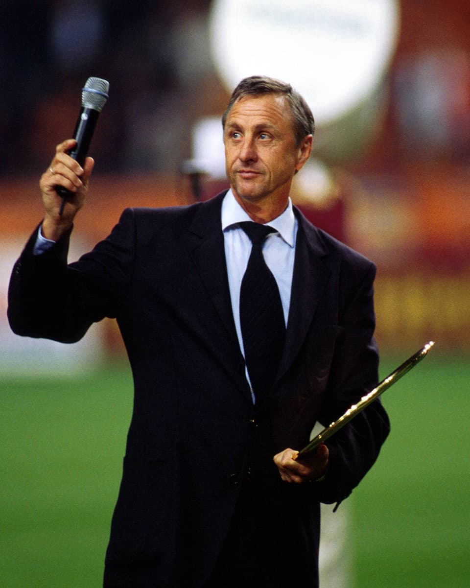 Cruyff hält Mikrophon in der Hand.