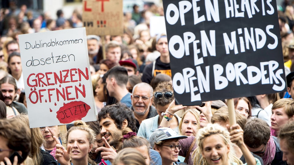 Eine Gruppe von Menschen hält Schilder in die Höhe, die für eine offene Asylpolitik in der Schweiz werben. 