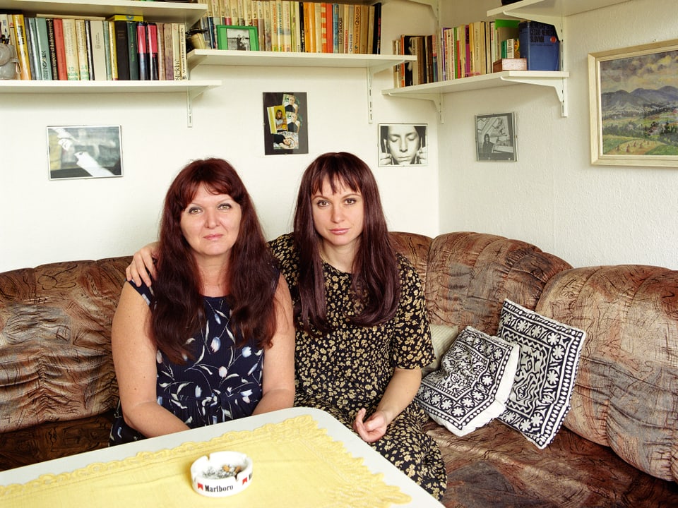 Zwei Frauen sitzen nebeneinander auf einem Sofa.