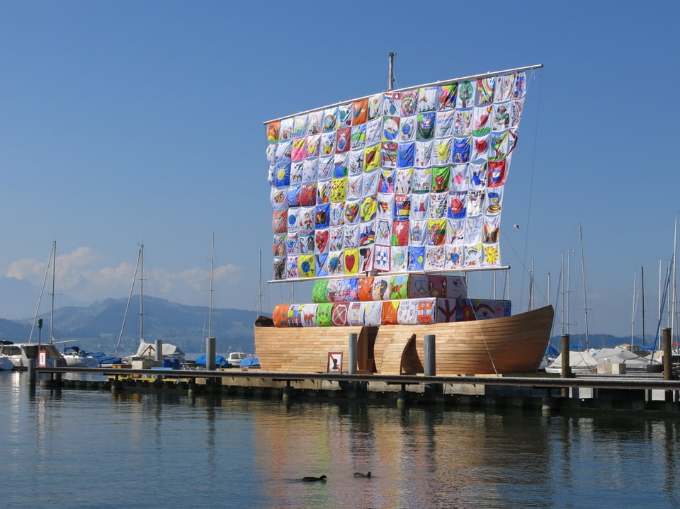 Ein Schiff mit buntem Segel liegt im Hafen.