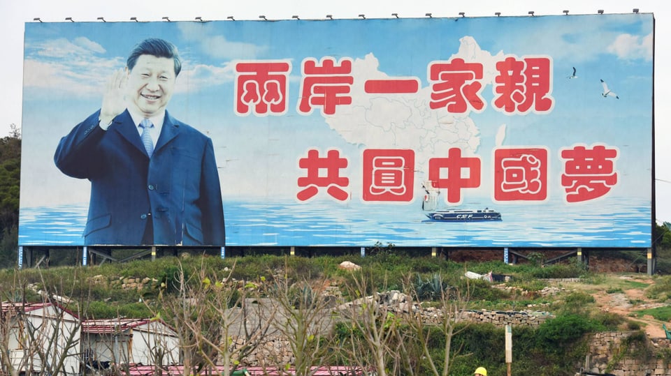 Ein blaues Plakat mit winkendem XI Jingping und roter chinesischer Schrift. Im Vordergrund eine Baulandschaft