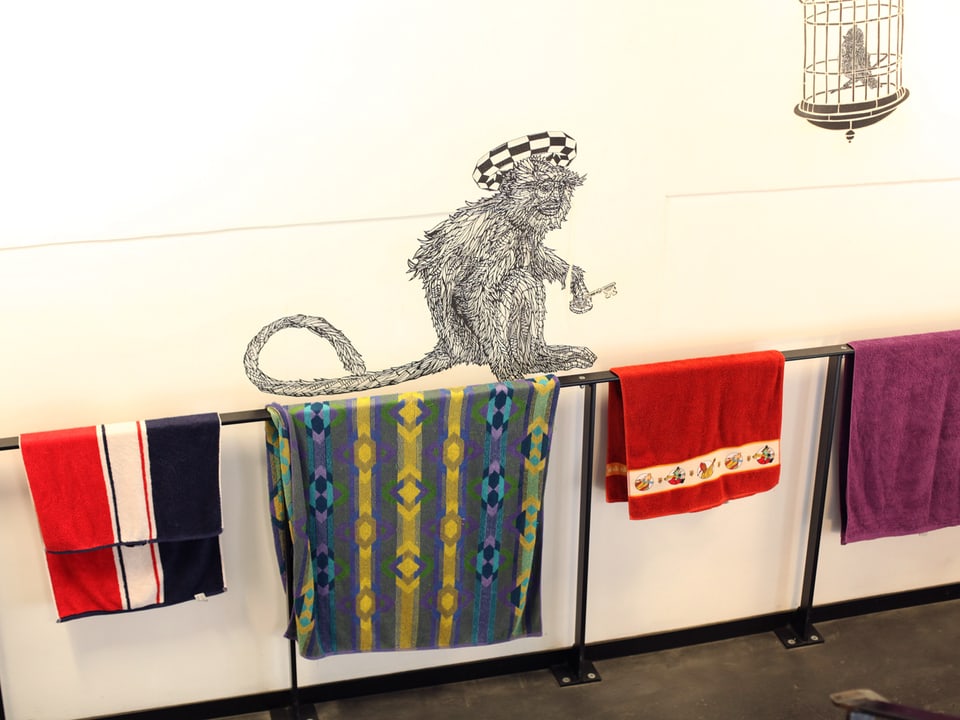 Handtücher hängen über ein Geländer, darüber ist ein Affe abgebildet.