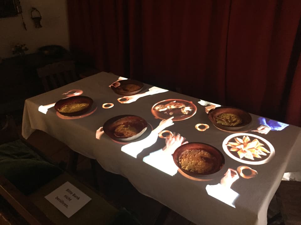 EIn Beamer projiziert ein Bild auf einen Tisch mit Essen.