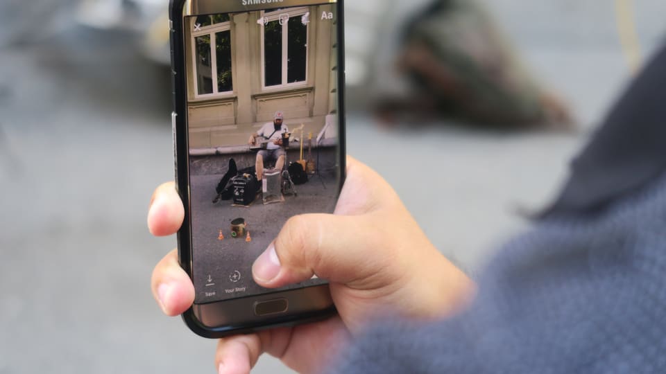 Handy mit einem Bild eines Strassenmusikers auf dem Display