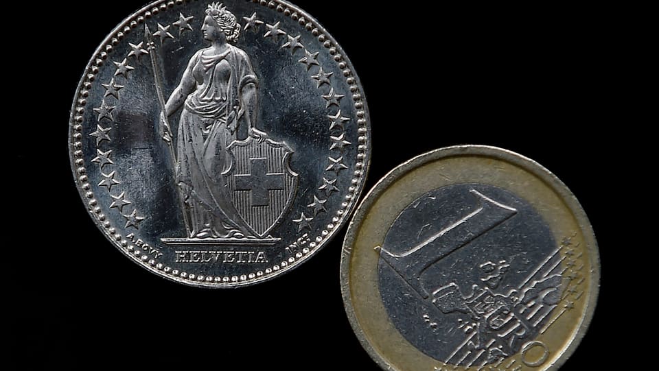 Eine Franken- und eine Euromünze auf schwarzem Grund.