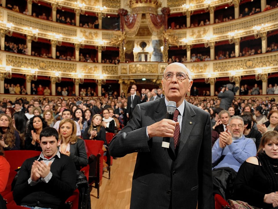 Napolitano spricht in einem voll gefüllten Theater in ein Mikrofon.
