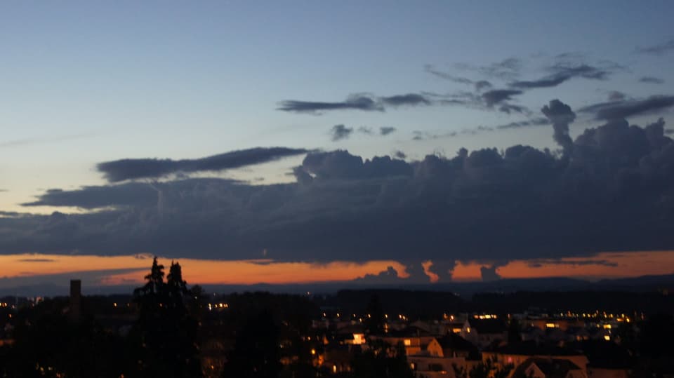 Oranges Band am Abendhimmel von Kreuzlingen, unterbrochen von Wolkentürmen.