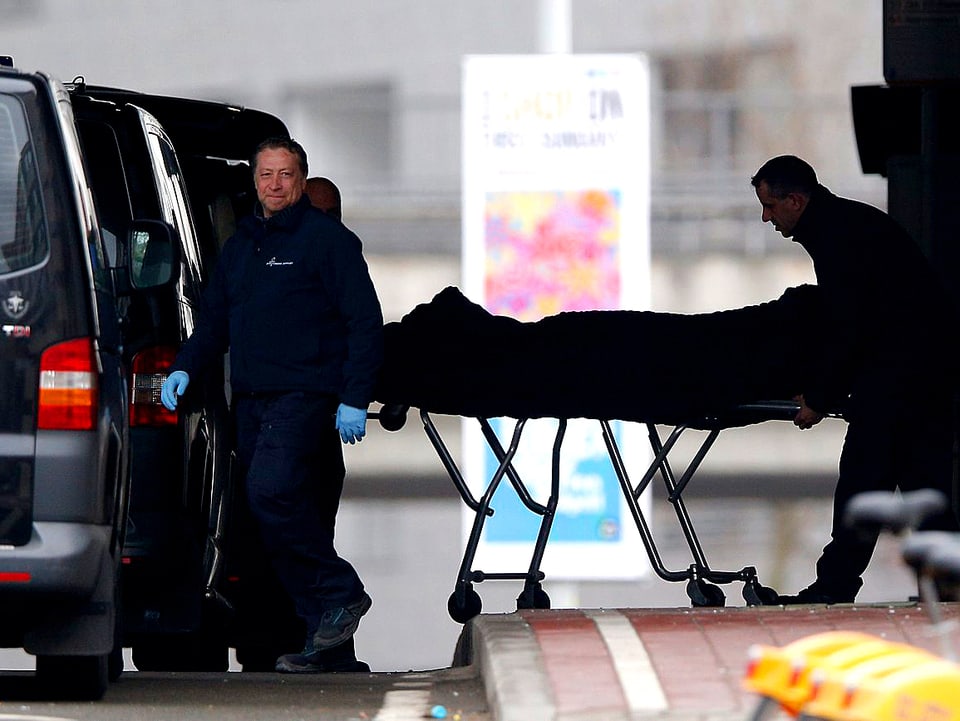Rettungskräfte transportieren auf einer Pritsche ein Opfer am Flughafen von Brüssel ab.
