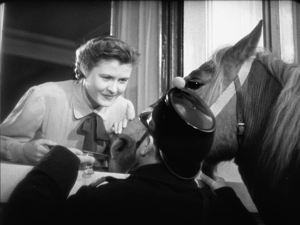 Eine Frau (Gilberte) lehnt sich zum Fenster hinaus zu einem Soldaten mit seinem Pferd.