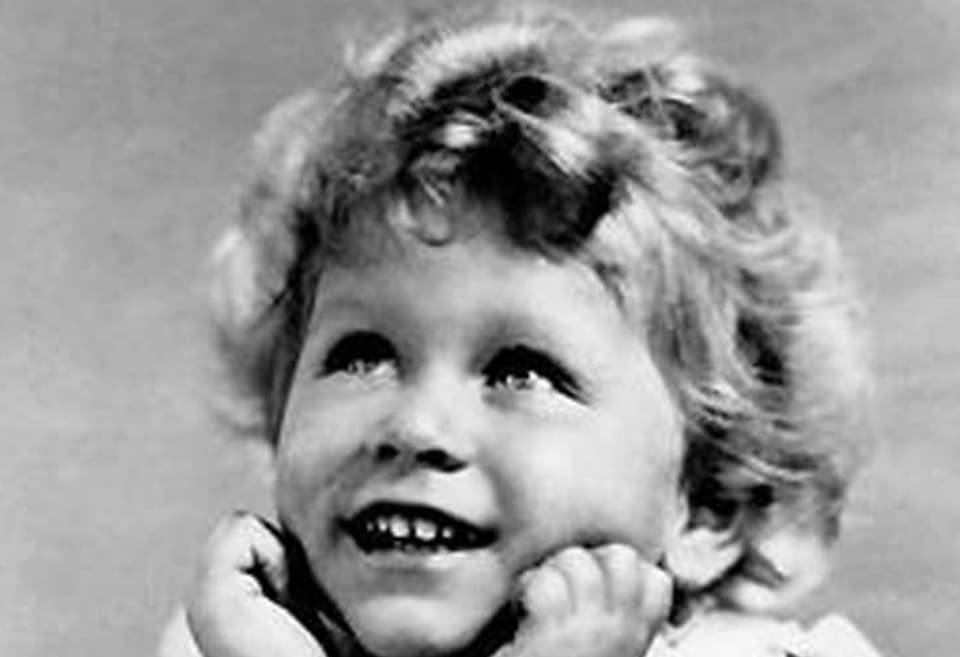 Schwarz-weiss Foto eines kleinen, lachenden Mädchens.