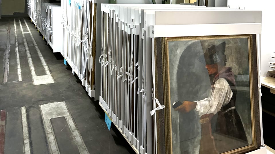 Auf dem Foto ist ein Kellerraum mit vielen gelagerten Gemälden zu sehen.