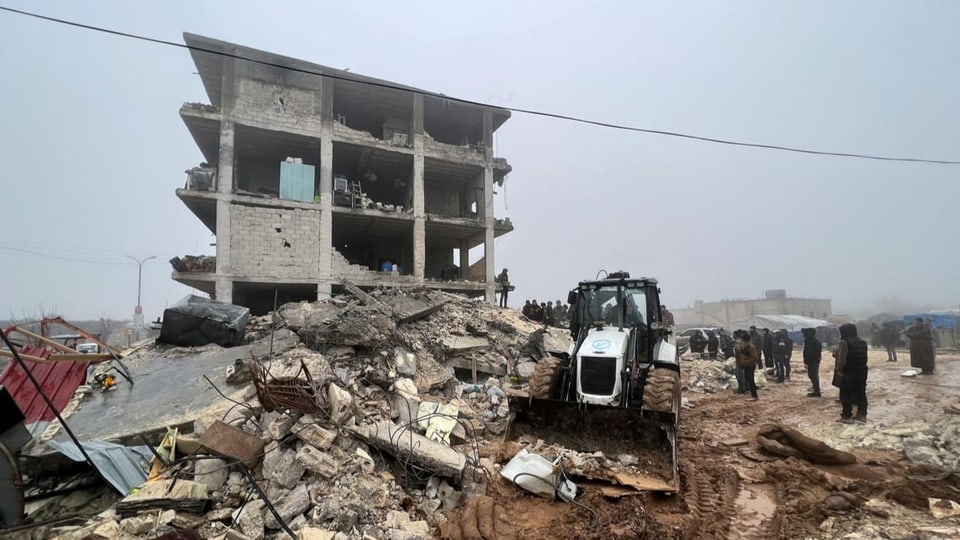 Menschen in Syrien stehen neben Trümmern nach der Erdbebenkatastrophe.