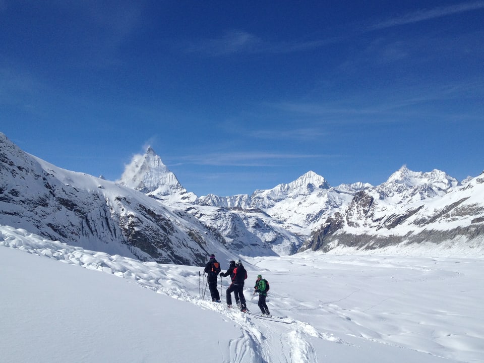 Gruppe Skifahrer mit Bergführer (in grüner Jacke), im Hintergrund das Matterhorn.