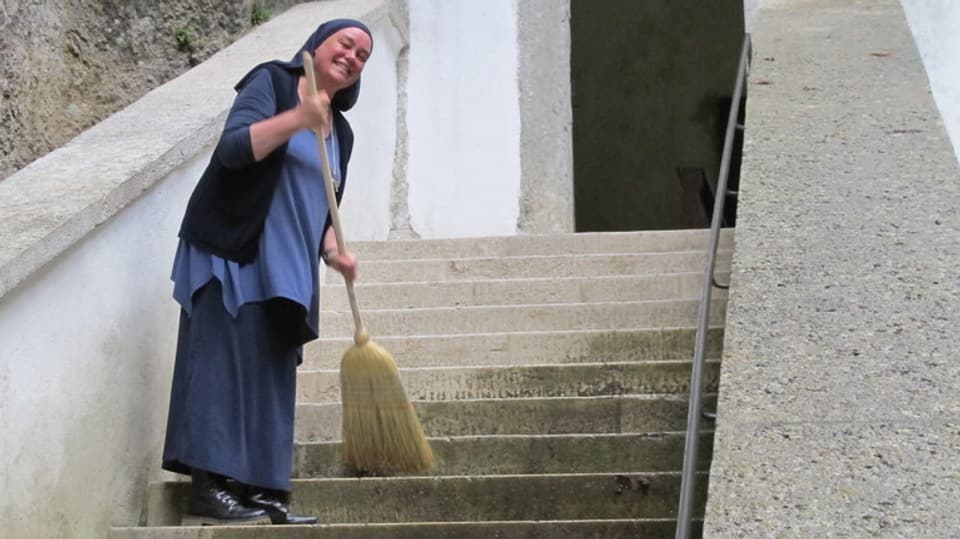 Frau mit Besen auf Steintreppe