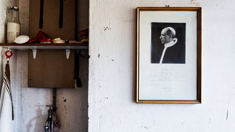 Eine Wand mit einem Bild des Papstes, golden eingerahmt.