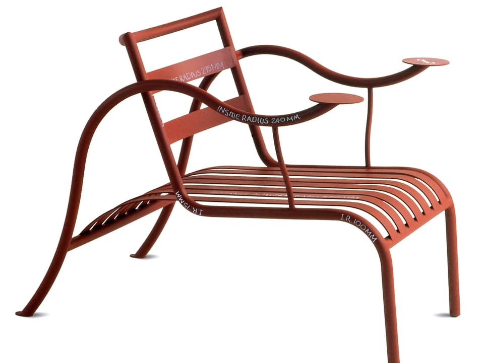 Ein geschwungener Sessel aus Stahlrohr versehen mit flachen Metallprofilen an der Rückenlehne und Sitzfläche.