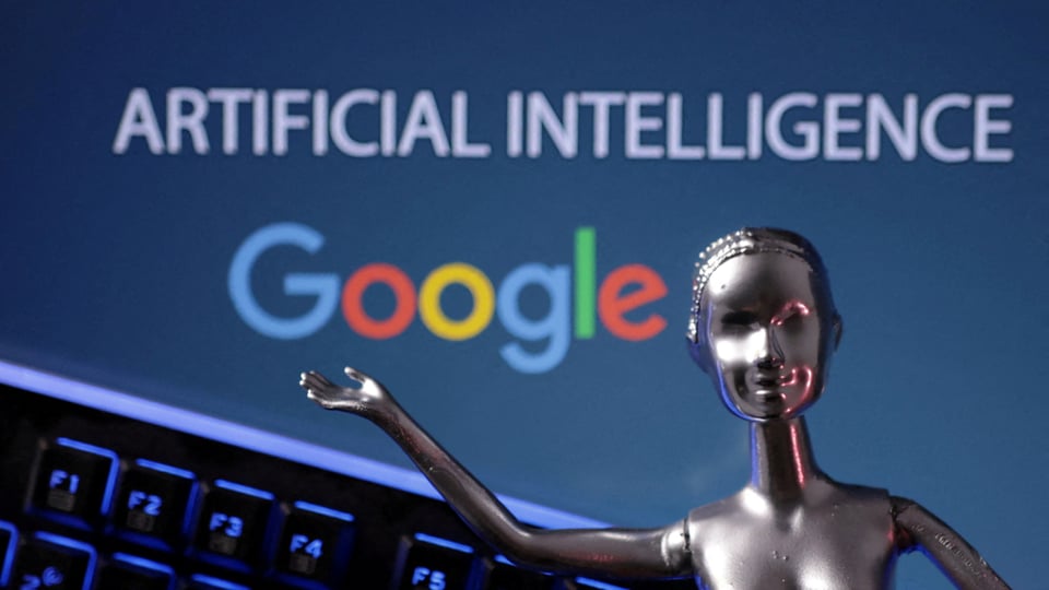 Bildschirm auf dem Artificial intelligence steht und das Google logo zu sehen ist. Davor die Statue einer Frau.