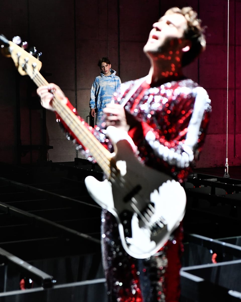 Ein Junge und ein Mann als Engel spielt Gitarre auf der Bühne.