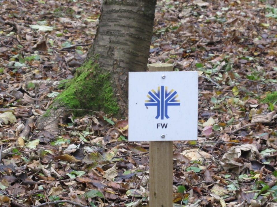 Schild, welches mit den Buchstaben FW auf den Friedwald hinweist. 