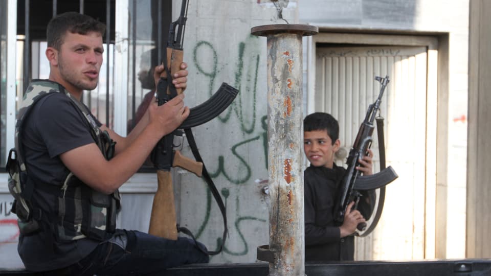 Ein junger Mann und ein Junge halten ihre Maschinengewehre in den Händen.