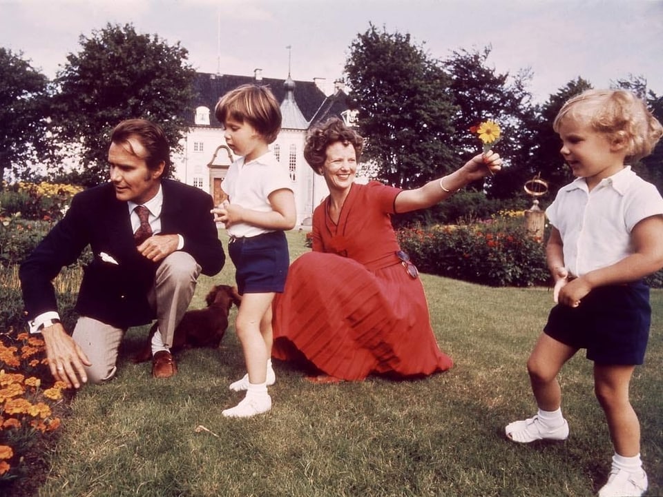 Königsfamilie auf einer Wiese. Das Bild wurde 1972 aufgenommen. Sie trägt ein rotes Kleid. Henrik einen Anzug und die beiden Jungs blaue Shorts und ein weisses Poloshirt.