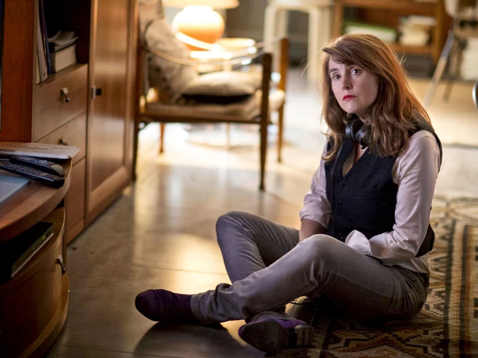 Regisseurin Marie-Castille Mention-Schaar sitzt mit überkreuzten Beinen auf einem Teppich.