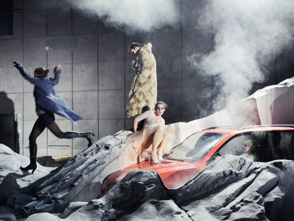 Auf der Theaterbühne: ein Auto, Felsbrocken, Rauch und vier Schauspielerinnen.
