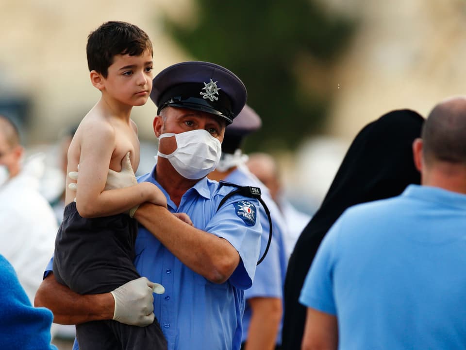 Ein Polizist hält ein Kind in seinen Armen.