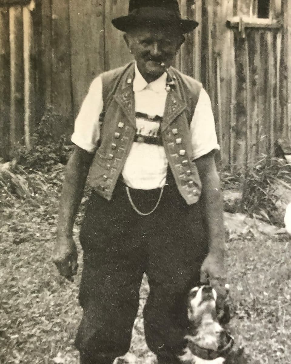 Ein alter Mann in Appenzeller Tracht mit einem Appenzeller Hund.
