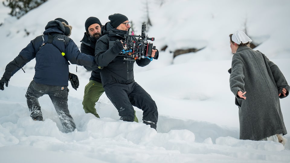 Kamerateam filmt eine Frau in historischem Kostüm im knietiefen Schnee.