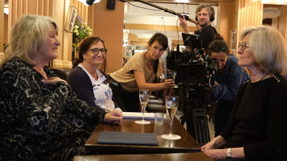 Drei Frauen, darunter Alice Schwarzer, sitzen am Tisch, hinter ihnen ein Kamerateam.