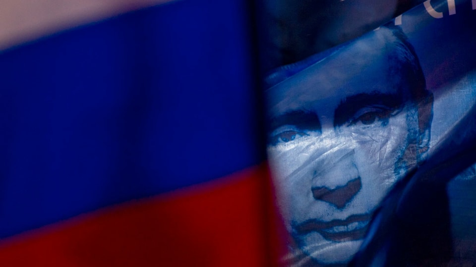 Putins Gesicht hinter russischer Flagge