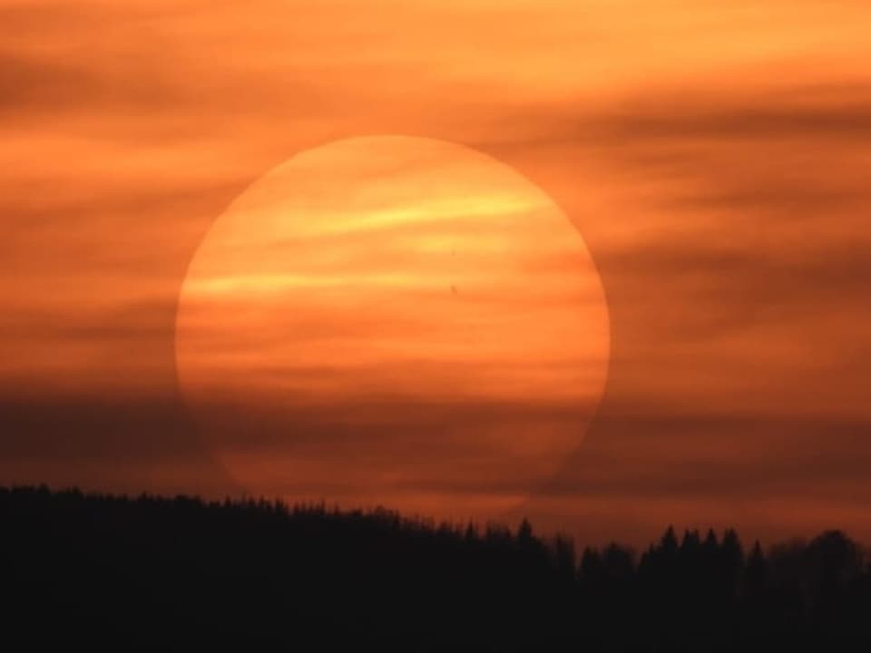 Gelb bis oranger Himmel mit Schleierwolken. Sonnenscheibe ist knapp zu erkennen. 