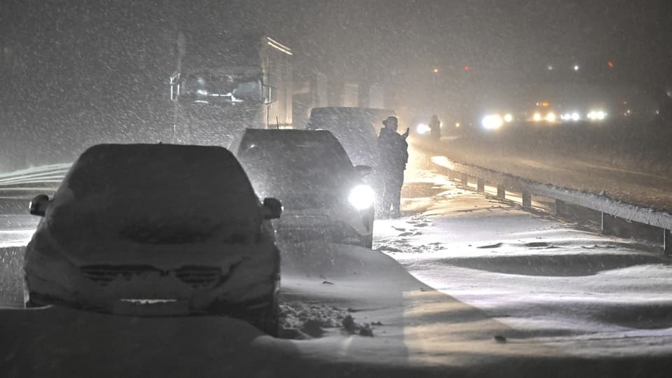 Autos stecken auf einer Strasse im Schnee fest. 