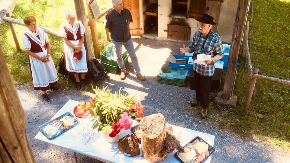 Der Lokalhistoriker Kurt Brigge und weitere Gäste bei der Übergabe des «Holztotz». Dieser steht auf einem Tisch, zusammen mit Blumen und einem Apéro.