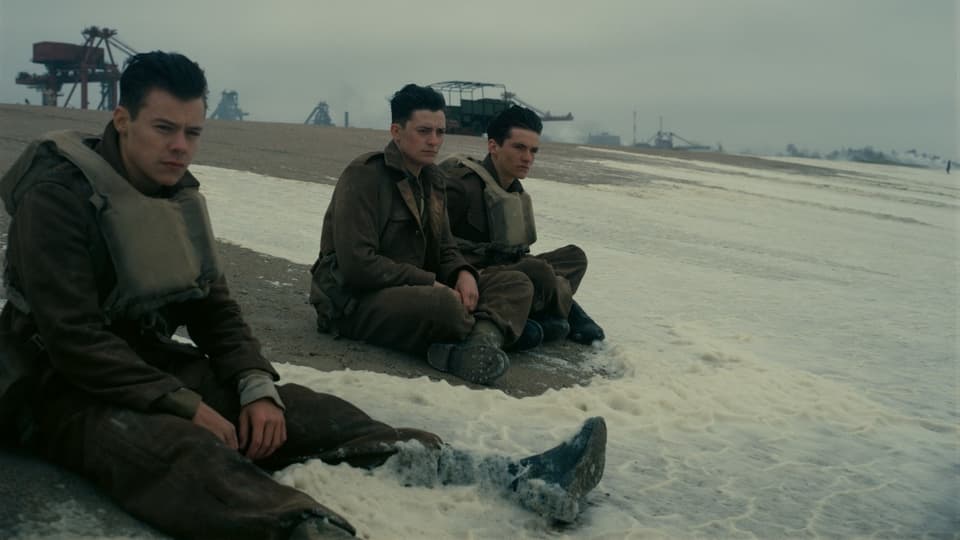 Drei Soldaten sitzen am Strand.