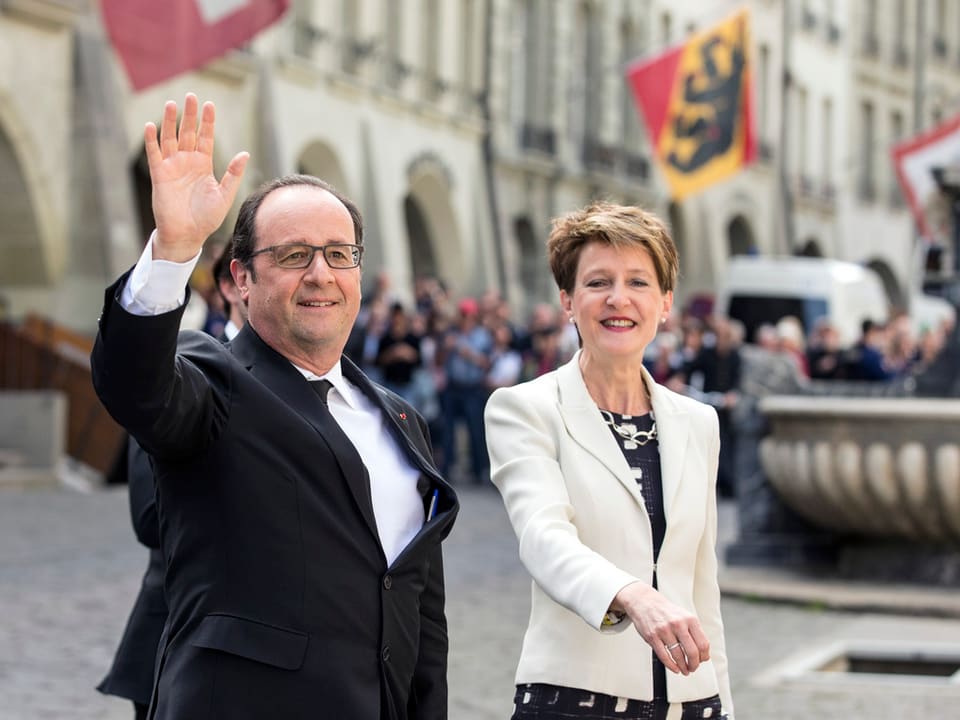 Hollande steht neben Sommaruga und winkt.