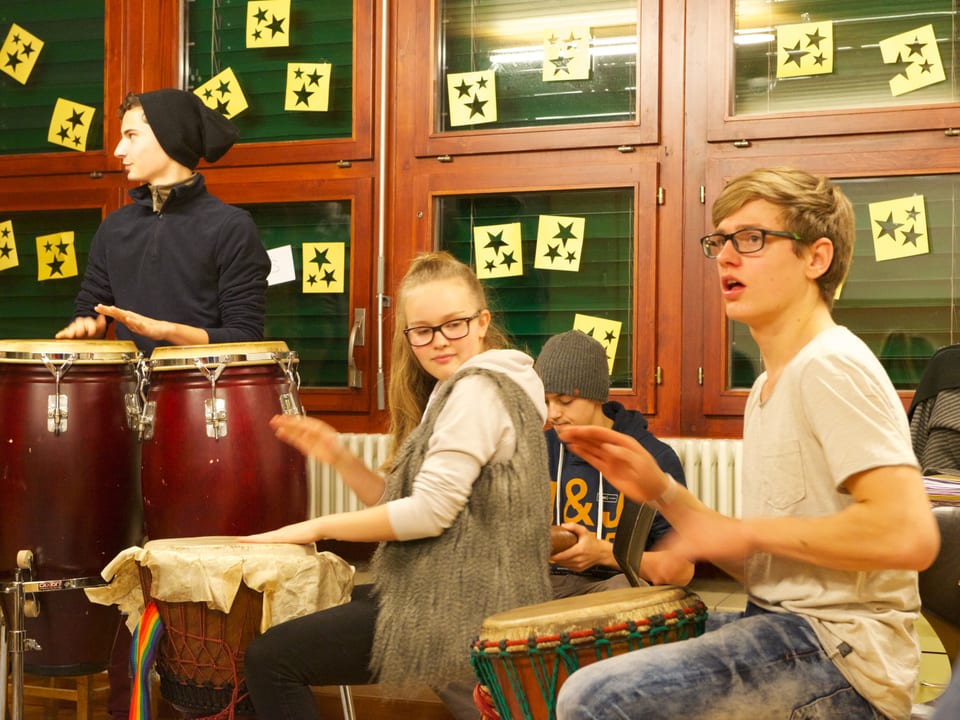 Vier Jugendliche spielen mit Trommeln.