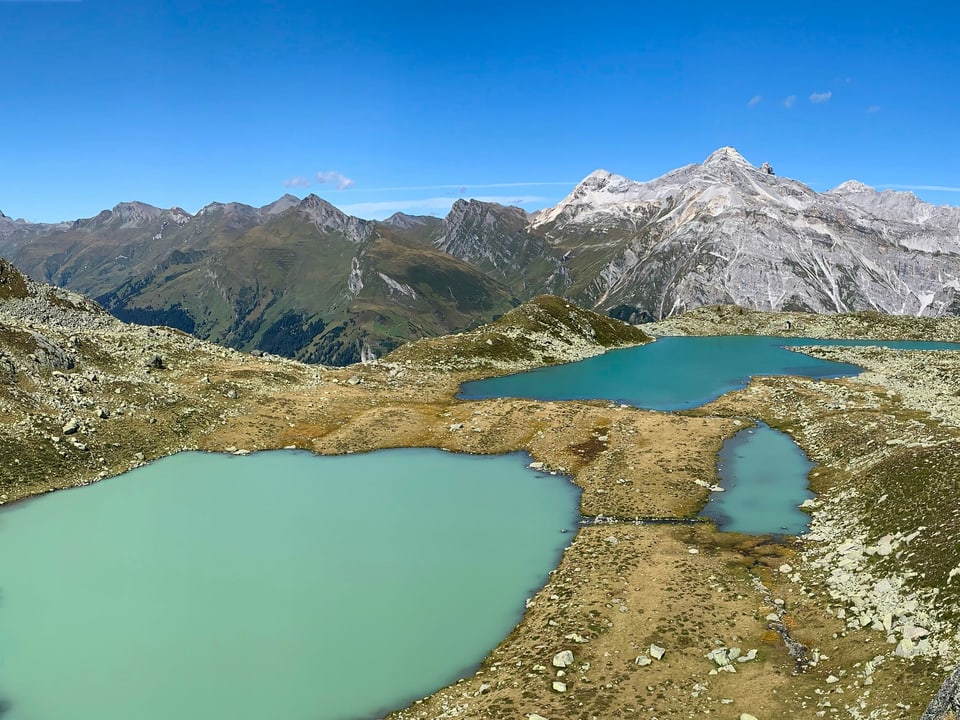 Sonnige Hochalpen ohne Schnee mit drei kleinen Seen im Vordergrund