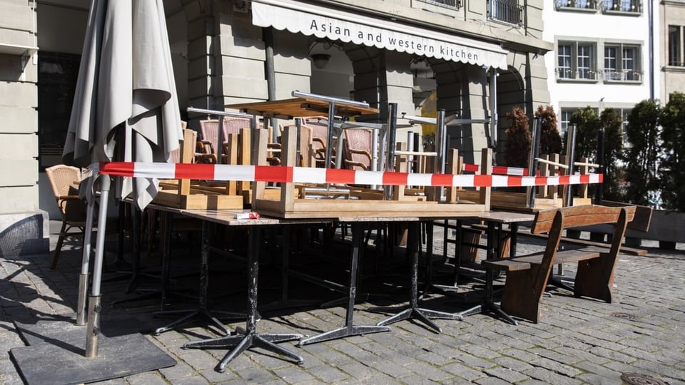 Tische und Stühle aufgetürmt vor einem Restaurant.
