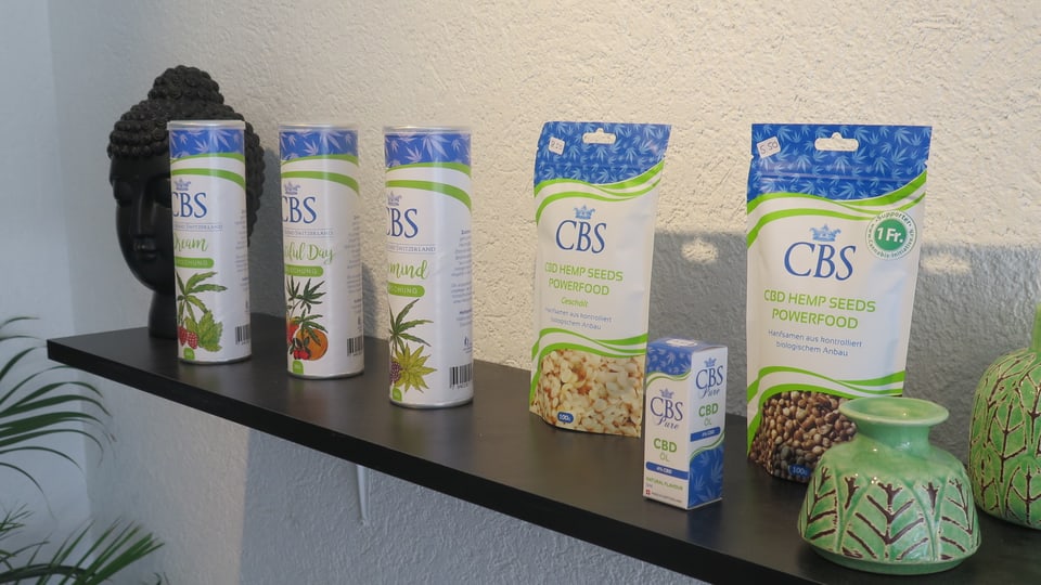 Auf einem Regal sind CBD-Produkte ausgestellt: Öl, Nahrungsmittelergänzungspulver.