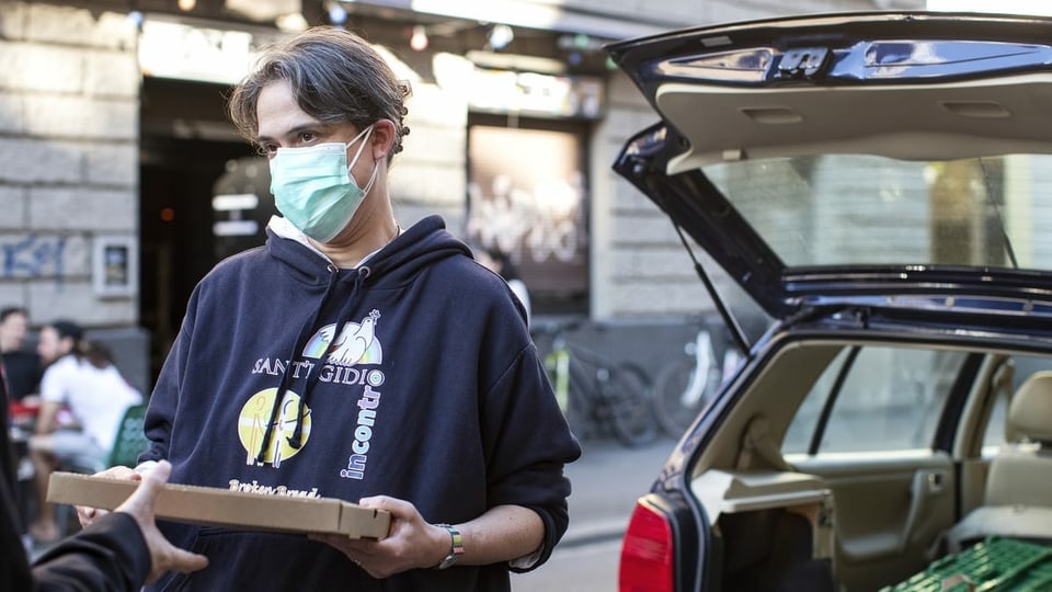 Eine Frau mit Schutzmaske verteilt Lebensmittel